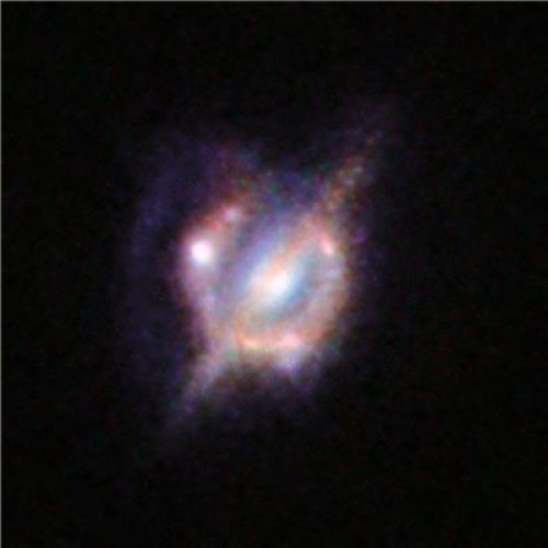 Questa imagine mostra la galassia lente (vista di taglio) circondata dall’immagine deformata, ad anello, delle due galassie lontane che si stanno scontrando. L’immagine è stata ottenuta attraverso Hubble e Keck.  Fonte: ESO/NASA/ESA/W. M. Keck Observatory