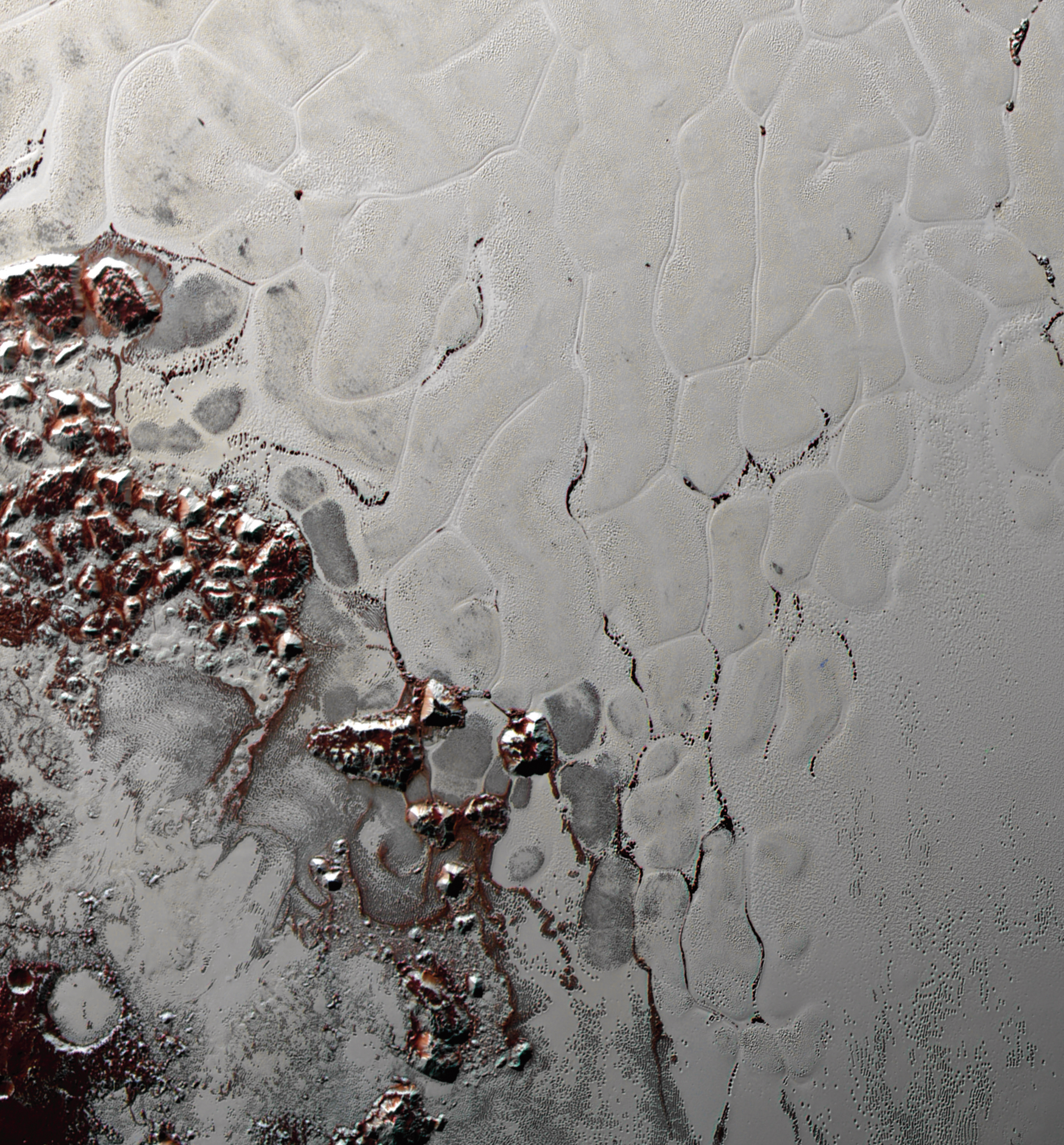 Una splendida vista delle bolle poligonali di ghiaccio d’azoto, che evolvono lentamente (per i nostri orologi…) e ringiovaniscono la superficie dell’immenso “cuore” di Plutone. Si notano anche i macigni di ghiaccio d’acqua e di metano, staccatisi dalle colline circostanti che vengono accumulati ai bordi della struttura. Fonte: NASA/Johns Hopkins University Applied Physics Laboratory/Southwest Research Institute.